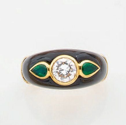 BAGUE jonc en or jaune et onyx sertis d'un diamant taille brillant épaulé de deux émeraudes de forme poire en serti clo
