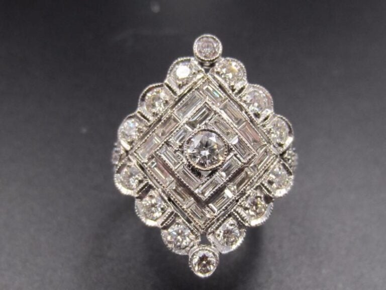 BAGUE « losange stylisé » en or gris (750 millièmes) ajouré à motifs de volutes serti de diamants taille brillant dont un, au centre , plus important entouré de diamants baguette