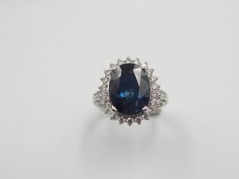 BAGUE «marguerite» en or gris (750 millièmes) serti d'un saphir de forme ovale pesant 5,75 carats entouré de petits diamants taille brillan