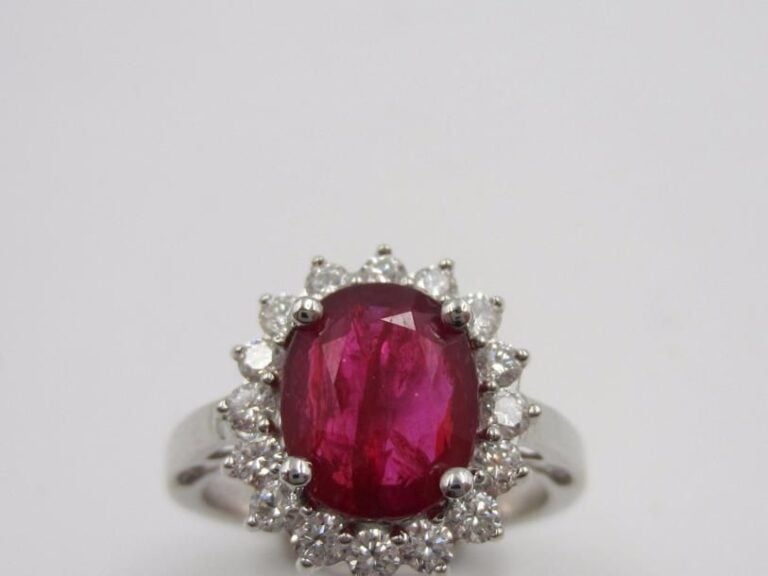 BAGUE « marguerite » en or gris (750 millièmes) serti d’un rubis de forme ovale pesant 3,06 carats, entouré de diamants taille brillan