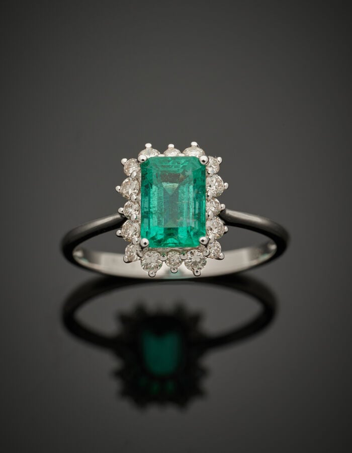 BAGUE "marguerite" en or gris (750‰) serti d'une émeraude taillée à degrés, ent…