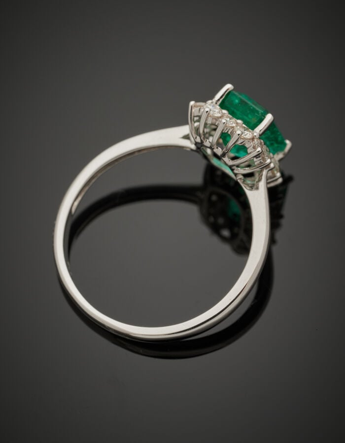 BAGUE "marguerite" en or gris (750‰) serti d'une émeraude taillée à degrés, ent…