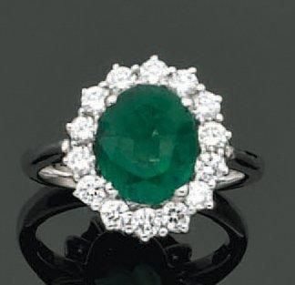 BAGUE «marguerite» en or gris serti d'une émeraude de forme ovale entourée de diamants taille brillan