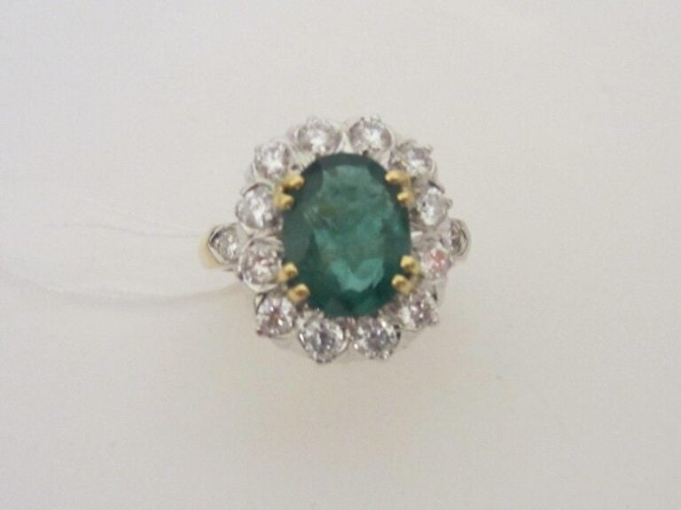 BAGUE «marguerite» en or jaune et or gris (750 millièmes) serti d'une émeraude de forme ovale, entourée et épaulé de diamants taille brillan