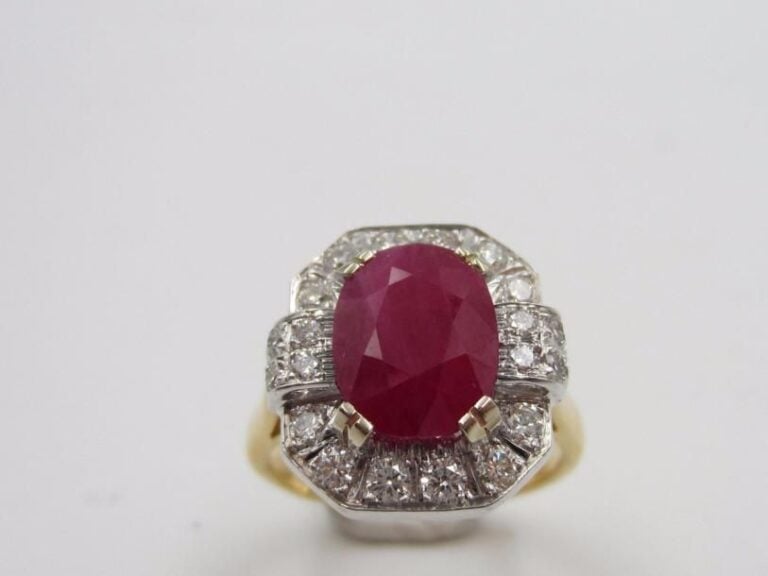 BAGUE octogonale en or jaune et or gris (750 millièmes) serti d’un rubis de forme ovale, pesant 3,39 carats, entouré et épaulé de diamants taille brillan