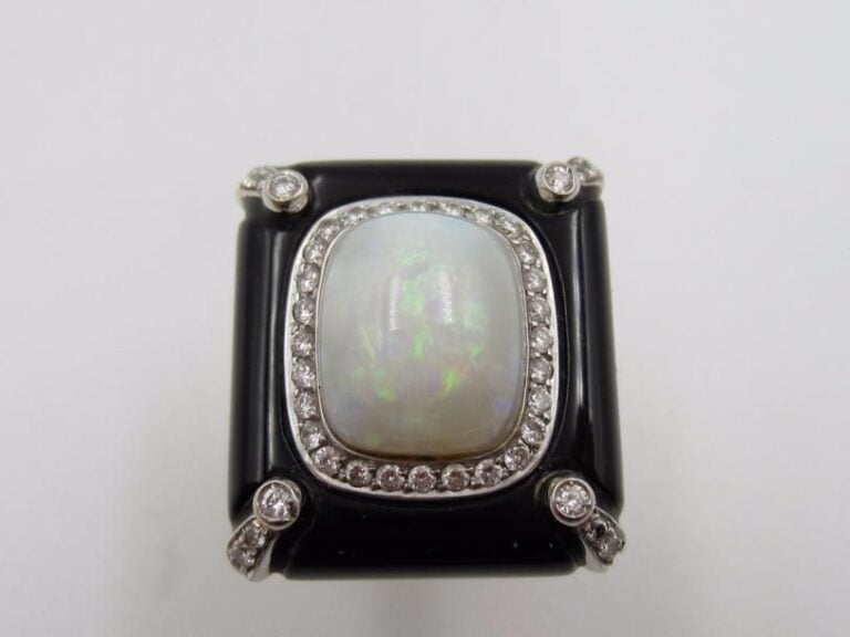 BAGUE or jaune et or gris (750 millièmes) serti d’une opale cabochon de forme coussin entourée et épaulée de diamants taille brillant rehaussé d ‘ony