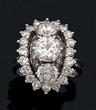 BAGUE ovale bombée en or gris (750 millièmes) serti de trois diamants taille ancienne entourés de diamants taille brillan