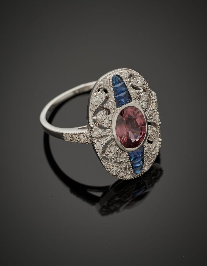 BAGUE ovale en or gris (750‰) finement ajouré de volutes, serti d'un zircon vio…