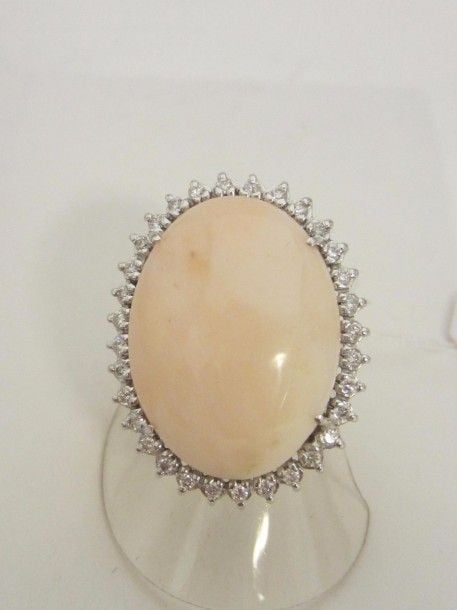 BAGUE ovale en or gris (750 millièmes) serti d’un important corail peau d’ange entouré de diamants taille brillan