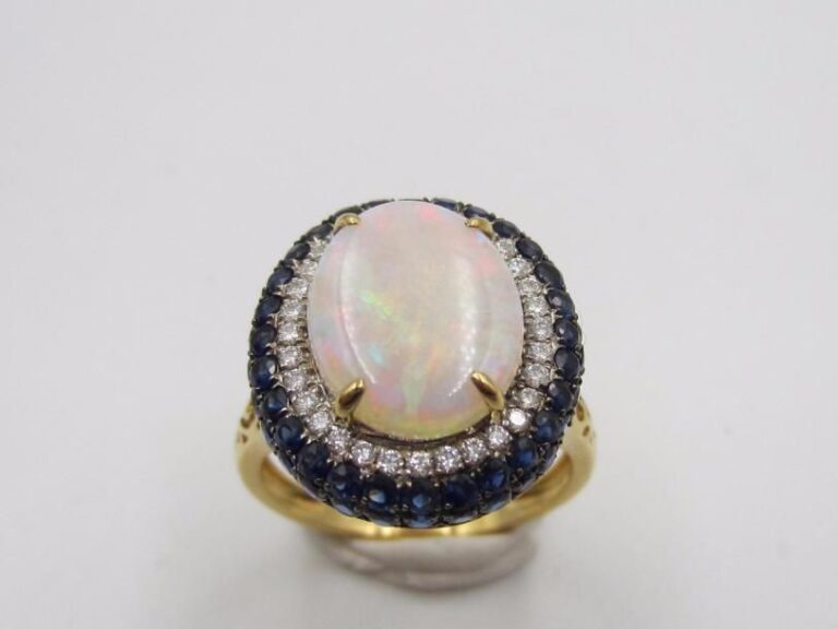 BAGUE ovale en or gris et or noirci (750 millièmes) serti d’une opale entourée de diamants taille brillant et saphir