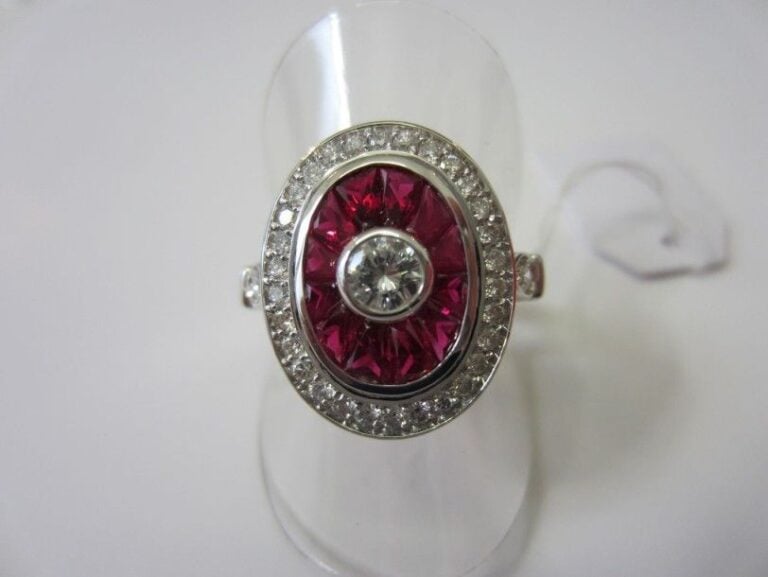 BAGUE ovale en or gris serti d'un diamant central entouré de rubis calibrés et de diamant