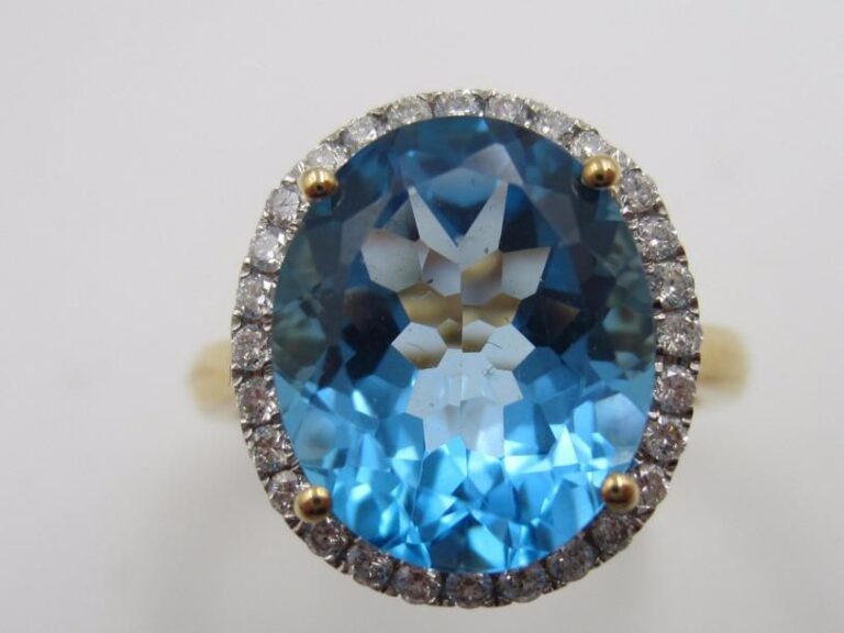 BAGUE ovale en or jaune et or gris (750 millièmes) serti d’une topaze bleue entourée de diamants taille brillan