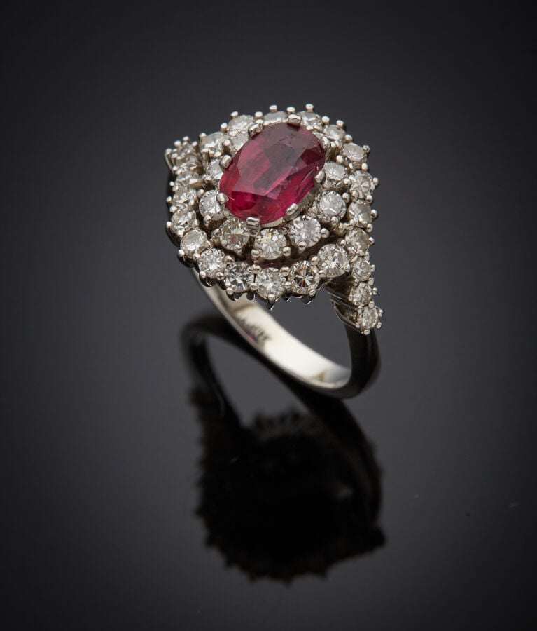 BAGUE "Pompadour" en or gris (750‰) centré d'un rubis de forme ovale (chocs), d…