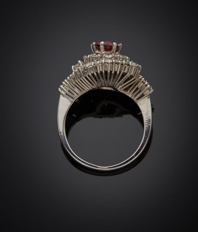 BAGUE "Pompadour" en or gris (750‰) centré d'un rubis de forme ovale (chocs), d…