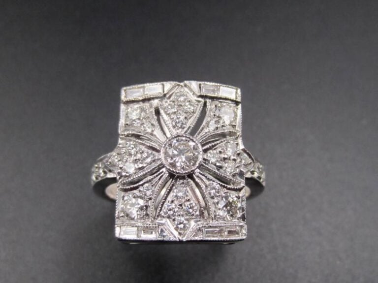 BAGUE rectangulaire en or gris (750 millièmes) finement ajouré à motif de « fleur » serti de diamants taille brillant et baguettes             Doigt : 53        Poids brut : 8,3 g