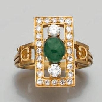 BAGUE rectangulaire en or jaune ajouré serti d'une émeraude cabochon de forme ovale épaulée et entourée de diamants taille brillan
