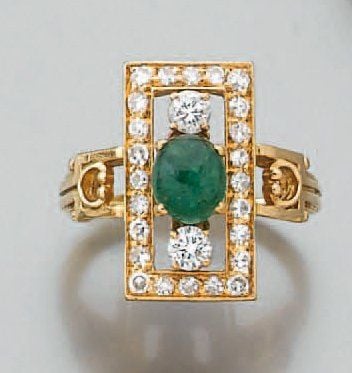 BAGUE rectangulaire en or jaune ajouré serti d'une émeraude cabochon de forme ovale épaulée et entourée de diamants taille brillan