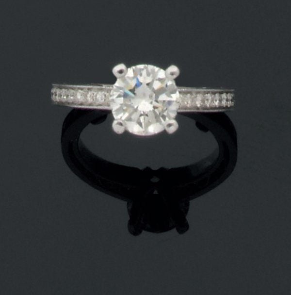 BAGUE solitaire en or gris serti d'un diamant de taille brillant pesant 1,65 carats environ, épaulé d'une ligne de diamants de chaque côté ; châton serti de petits diamants (dont un manquant