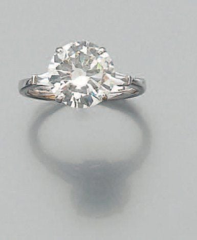 BAGUE solitaire en or gris serti d'un diamant demi-taille épaulé de diamants taeper