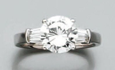 BAGUE solitaire en or gris serti d'un diamant taille brillant épaulé de six diamants taeper