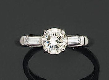 BAGUE solitaire en or gris sertie d'un diamant de taille brillant épaulé de deux diamants baguette