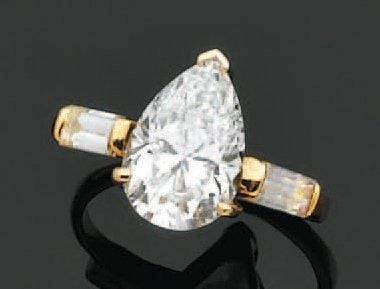 BAGUE solitaire en or jaune serti d'un diamant de forme poire pesant 4,08 carats, épaulé de diamants baguette