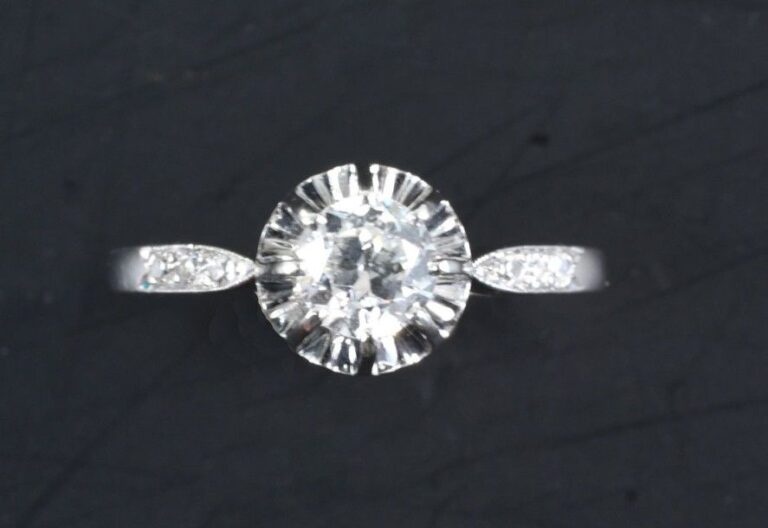 Bague solitaire en platine sertie griffes d'un diamant de taille ancienne, épaulé de deux demi lignes de diamants taille 8/8 Tour de doigt: 58 Poids brut: