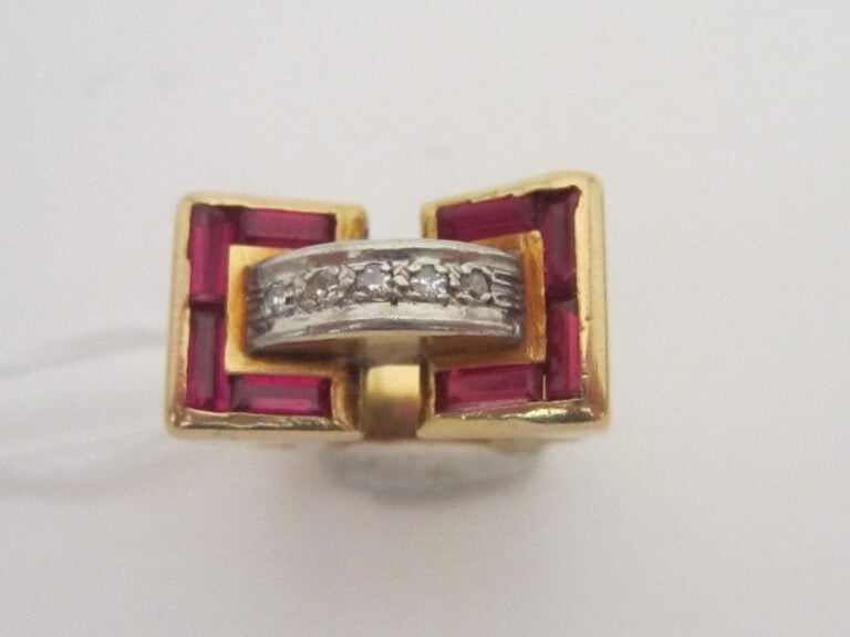 BAGUE «tank» en or jaune et or gris (750 millièmes) ajouré «à livre ouvert» serti de pierres rouges calibrées, reliée par un «pont» serti de diamants 8/