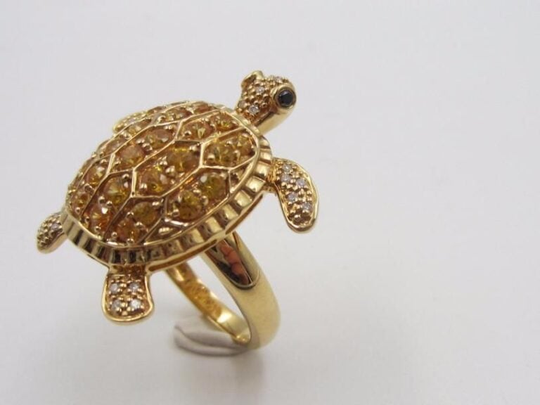 BAGUE « tortue » en or jaune (750 millièmes) godronné, pavé de saphirs jaunes entouré de diamants taille brillant, les yeux sertis de deux diamants noir