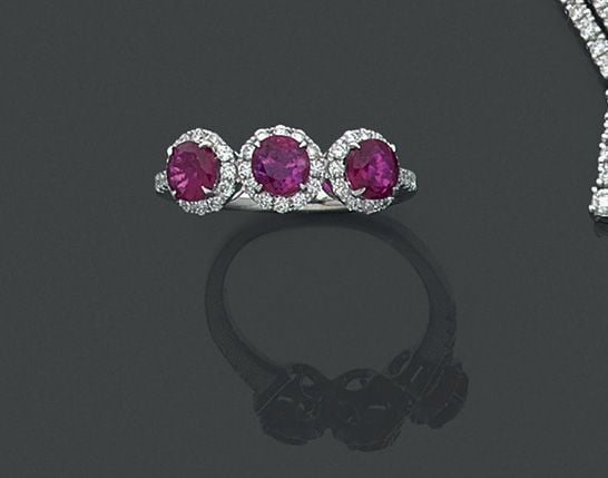 BAGUE « trilogie » en or gris (750 millièmes) serti de trois rubis ronds entourés de diamants taille brillan