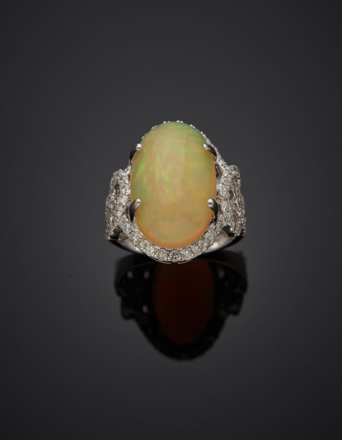 BAGUE "volutes" en or gris (750‰) ajouré, orné d'une opale cabochon de forme ov…