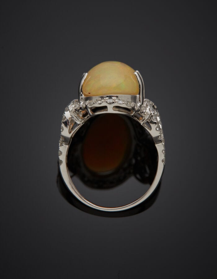 BAGUE "volutes" en or gris (750‰) ajouré, orné d'une opale cabochon de forme ov…