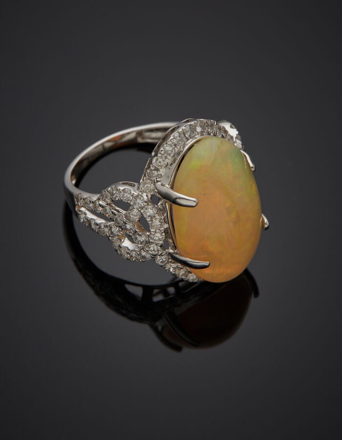 BAGUE "volutes" en or gris (750‰) ajouré, orné d'une opale cabochon de forme ov…