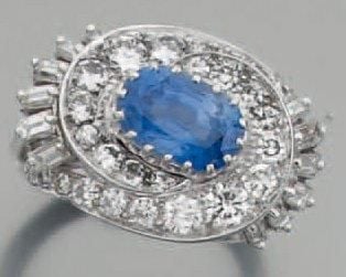 BAGUE « volutes » en platine ajouré serti au centre d'un saphir de forme ovale entourée de diamants baguette et taille brillan