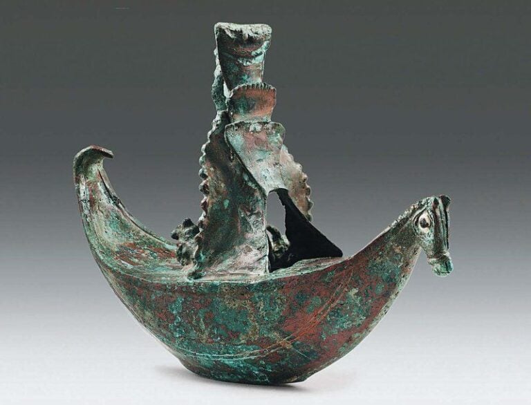 BARQUE VOTIVE Barque de forme elliptique, à proue en forme de tête de cheval aux yeux incrustés, portant en son milieu une construction en forme de tour, flanquée à sa base par deux animaux et longée par deux serpent
