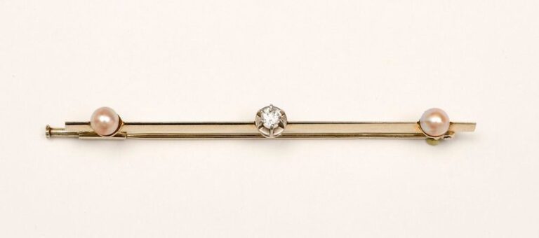 BARRETTE EPINGLE en or gris ornée d’un diamant rond serti à griffes et de deux demi-perle