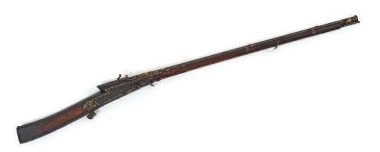Beau mousquet à mèche - Toradar Inde, circa 1800 Longueur: 145 cm Le canon en acier à décor de fleurs et de cyprès maintenu par deux capucines rapportées, le fût orné de grosses fleurs et d'oiseaux affrontés gravés et dorés sur fond d'acier maté, la crosse en bois à la belle patine caramel