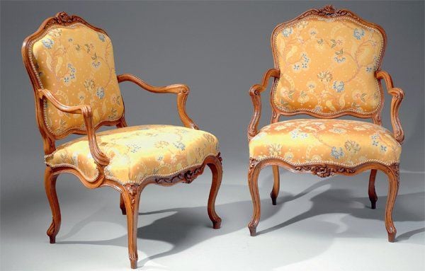 Belle paire de fauteuils à dossier plat, en noyer richement sculpté de fleurettes et de feuillages dans des encadrements nervuré