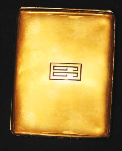 BOÎTE à cigarettes rectangulaire aux coins arrondis en or jaune surmonté d'un monogramme « GG » en émail bleu et serti sur une tranche d'un alignement de pierres bleues synthétiques alternées de diamants de taille ancienne dissimulant le fermoi