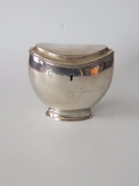 Boîte à thé en argent uni sur piédouche, bordure perlée ; petite serrure en façad