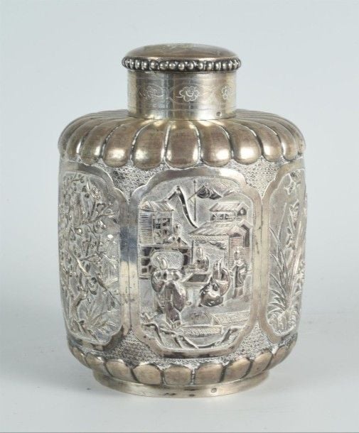 Boîte à thé ovoïde et godronnée en argent Chinois d'exportation ornée au repoussé sur son pourtour de médaillons figurant le thème des "Quatre Saisons" ainsi que des pies, des papillons et des immortels taoïstes ; au centre, un blason chiffré ; marque de l'atelier au dessous ; Chine, circa 1780-1820 (petits enfoncements) ; poinçons d'importation "Charançon" adjoints de la lettre "M