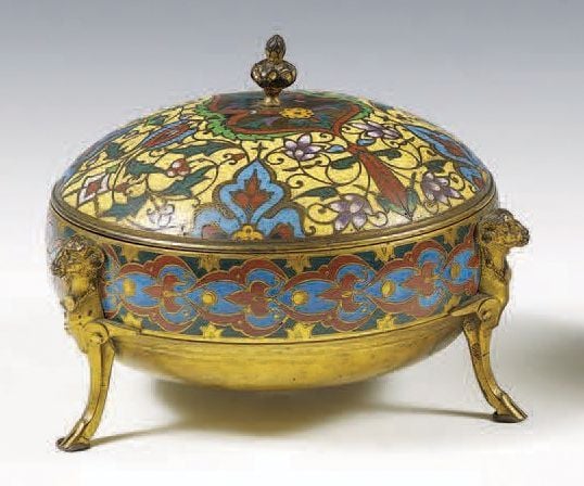 Boîte circulaire en bronze et émaux cloisonnés polychromes; le couvercle bombé terminé par un bouton stylisé; piétement tripode à têtes et pattes de bélie