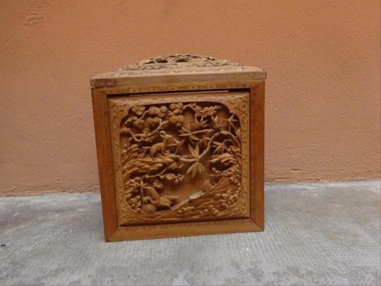 BOITE COUVERTE QUADRANGULAIRE ET BOMBEE EN BOIS FRUITIER SCULPTE Probable travail de Chine du Sud ou du Tonkin (Vietnam) des alentours de 1900 En bois naturel, à monture quadrangulaire recevant quatre panneaux, un pour chaque côté, auxquels vient s'adjointe le panneau du couvercl