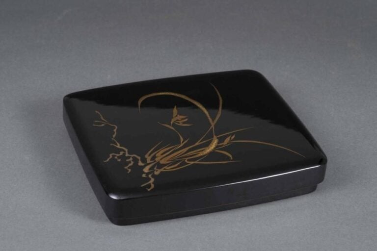 BOITE ECRITOIRE EN LAQUE NOIRE A DECOR D'UNE PLANTE HERBACEE, SUZURI BAKO Japon, Epoque XXe siècle, Période Showa De forme rectangulaire et à bords arrondis, elle présente un couvercle, dévoilant un intérieur avec un compartiment amovibl