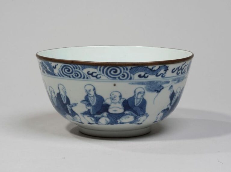Bol en porcelaine à décor en bleu sous couverte des dix-huit luohan, surmontés d'une frise à motifs de dragons dans les nuée