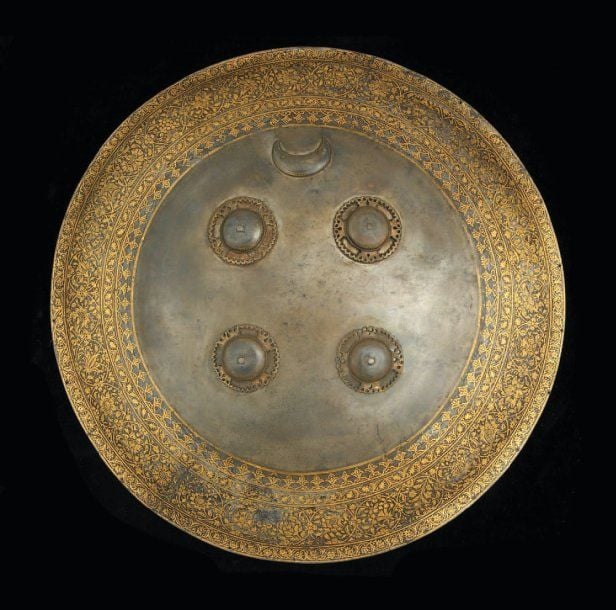 BOUCLIER Rondache circulaire à quatre bossettes et croissant riveté, en acier damasquiné d'or (koftgari), décorée de quatre bandeaux concentriques renfermant guirlande, rondeaux floraux et rinceau