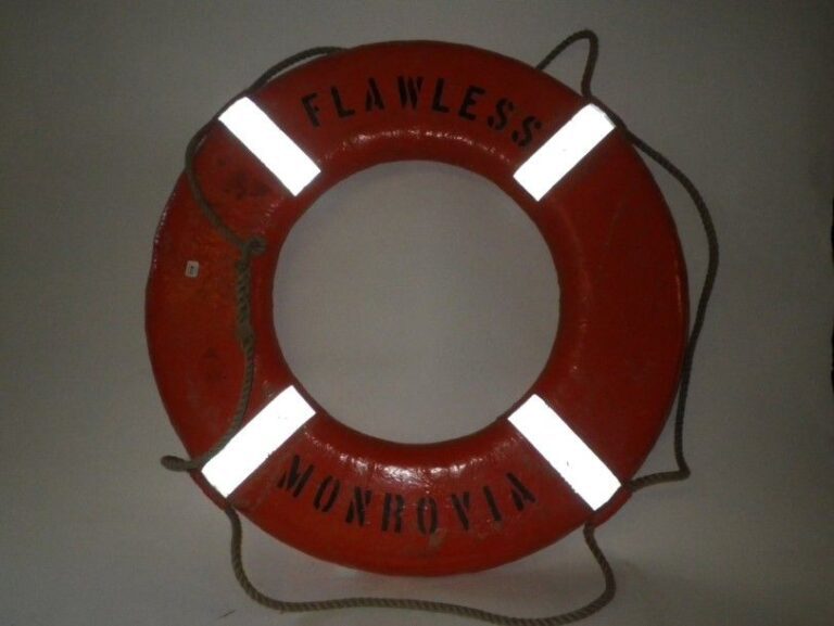 Bouée de sauvetage en liège recouverte d'une toile peinte en orange et portant l'inscription «Flawless - Monrovia» Dia