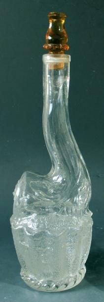 Bouteille en verre moulé en forme de pipe posée sur une blague à taba