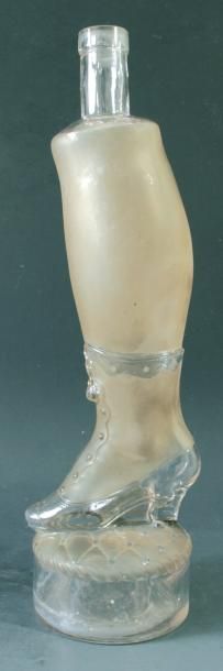 Bouteille en verre moulé représentant une jambe de femme satinée avec bottine posée sur un coussi