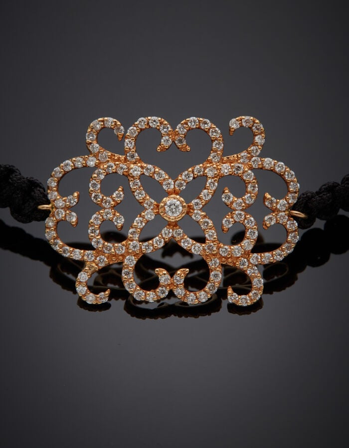 BRACELET "arabesques" composé d'un cordon noir tressé retenant un motif en or r…